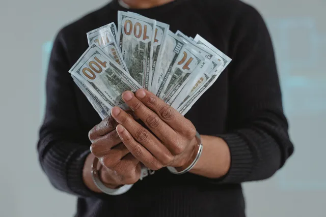 Close-up of hands holding 100-dollar bills while handcuffed, symbolizing crime and punishment. Affiliate fraud and attribution disputes